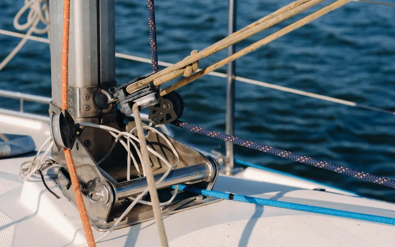 Jarcia y cabos tensados sobre la cubierta de un velero, con el mar al fondo.